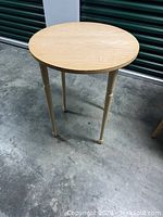 Front angle view of the round wooden table showing the tabletop and legs with caster wheels.