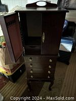 Front view of the vintage wood jewelry armoire showing open doors revealing interior storage compartments.