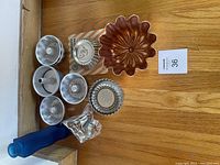 Photo showing eight different vintage baking and jelly molds arranged on a wooden surface, highlighting their shapes and materials.