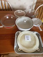 View of seven kitchenware items on a wooden table including clear glass bowls and white ceramic dishes.