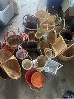Photo showing a diverse assortment of baskets, multiple colors and sizes, assorted natural and dyed wicker material, some with handles.
