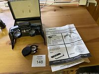 Abrams foldable photo interpretation instrument with additional lens and instruction sheet on wooden table