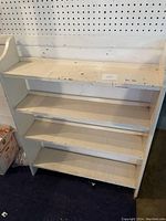 Front view of the white wooden shelving stand showing three shelves and back panel.