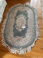 Top view of small oval carpet showing floral pattern and fringes.