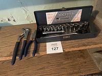 Overview photo of socket set and two pliers on wooden surface