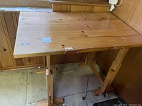 Full view of the wooden adjustable height table showing the top surface and supporting base