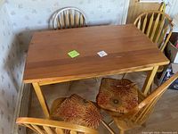 Wooden dining table with four matching chairs, showing table top and chair design.