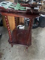 Wooden wash basin stand with twisted spindle legs. The stand is missing its wash bowl and is unpackaged on the floor with other stored items around.