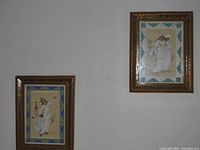 Two framed Persian paintings on bone hung on wall showing detailed figures and ornate frames