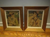 Photo showing two framed vintage child portrait prints next to each other on hardwood floor.