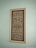 Full view of the framed antique Chinese embroidery panel hanging on a wall, showing the vertical rectangular format and wooden frame with a light finish.