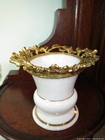 Antique white china vase with gold plated ornate leaf design around mouth, bulbous base, and gold accents