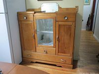 Front view of antique wooden hutch with glass door, drawers, two side doors, and mirror on top back panel.