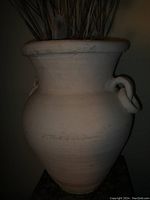 Full view of the large terracotta vase with dried plants inside, showing its body and handles.