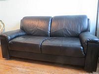 Front view of black leather loveseat showing overall condition and shape.