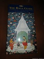 Closed cover of The Raga Guide book showing traditional Indian artwork with musicians and floral design