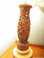 Front side view showing entire lamp stand with carved figure and floral patterns on wood surface.