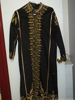 Full front view of vintage black felt coat with gold embroidery extending down the center and along the edges and sleeves.