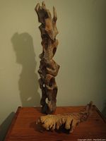 Photo shows the tall totem wood carving with abstract shapes and rough texture, highlighting cracks and minor damage at upper sections
