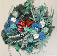 Top view photo of the decorated Christmas wreath showing the green branches and blue, silver, and red decorative accents.