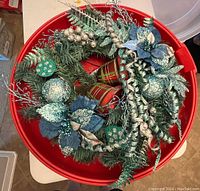 Top view of the decorated 19 inch Christmas wreath inside the red plastic storage box.