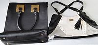 Photo of two large handbags, one black structured with gold-tone hardware, one black and white Nine West shoulder bag with tassel detail.