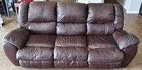 Full view of the three-seat brown leather recliner couch, showing plush cushions, armrests, and overall shape.