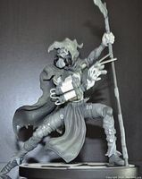 Front left angle of the Scarecrow statue showing the detailed sculpting, tattered cloak, and dynamic stance holding a staff.