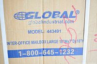 Close-up photo of the cardboard box packaging of the mailbox showing brand Global Industrial, model number 443491, and dimensions 18"W x 7"D x 18"H.