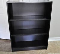 Front view of Ikea BILLY bookcase showing three shelves in black-brown finish