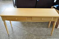Full view of the light wood sideboard buffet with two drawers and tapered legs.