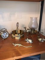 Full view of the shelf showing clock, ashtray with emblem, camel, lamp, two mice, and lizard figurine