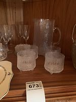 Bottom shelf display showing four textured glass tumblers in front and matching textured glass pitcher behind