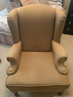 Front view of beige wingback armchair showing high backrest, winged sides, and rolled armrests.
