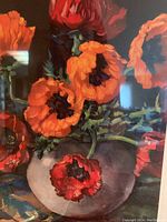 Close-up of framed floral artwork showing vibrant orange flowers in a vase.