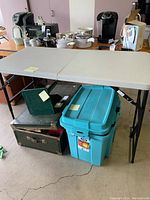 Full view of folding table showing top surface and black metal folding legs with some items around it.