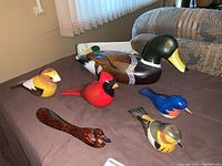 Photo showing the full lot of five handcrafted wooden bird figurines arranged on a table.