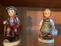Four Hummel porcelain figurines each depicting children in various poses and clothing styles.