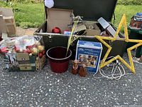 Wide shot showing vintage green trunk opened, yellow star light, red pot, bags of Christmas ornaments, and box of decorations