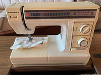 Front view of Janome SX 2122 sewing machine on cabinet, showing stitch pattern panel and control dials with fabric set up for sewing.