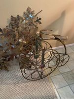 Side angle of brass wine holder with circular ring design for holding multiple wine bottles, showing minor discoloration.