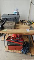 Full view of table with tools and storage boxes including hatchet, saw, hammer, and pliers