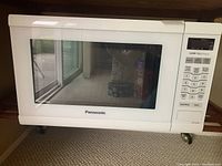 Front view of Panasonic white microwave oven showing digital keypad and brand logo