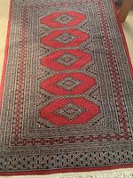 Close-up of area rug with red diamond pattern and detailed geometric borders.
