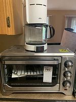 Braun coffee maker on top of chrome Oster toaster oven on kitchen counter