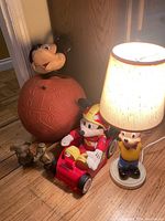 Photo showing all five items including Mickey Mouse head on round base, two small brass Mickey figurines, racing Mickey in go-kart, and Donald Duck lamp.