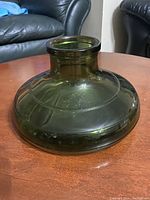 Front side of green glass Christmas tree stand showing wide base and narrow neck.