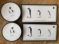 Top view of 2 round cocktail plates stacked, and 2 rectangular platters with penguin designs.