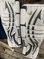 Close-up of the front of the Vaughn Velocity goalie pads showing white base with black and gray accents, branding, and model name.
