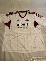 Front view of white Adidas West Ham United jersey with sponsor and club crest details.